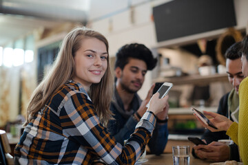 Young adult friends using smart phones at cafe table