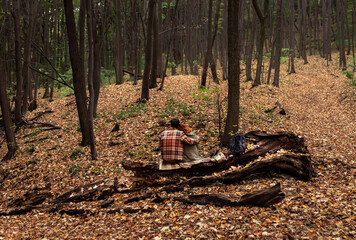 Young couple with backpack resting after hiking in forest.