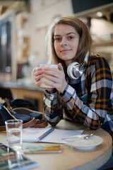 Portrait confident young female college student studying at cafe table