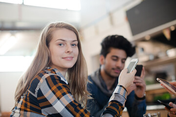 Young adult friends using smart phones at cafe table