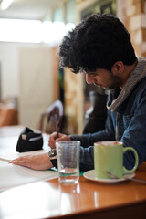 Portrait confident young male college student studying in cafe