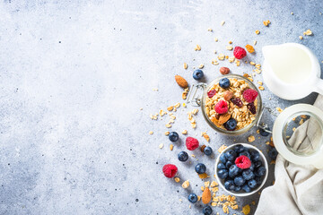 Granola with fresh berries and milk. Baked oat flakes Healthy breakfast or dessert at light stone table. Top view with copy space.