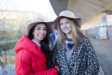 Portrait confident young women wearing fedoras along canal