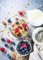 Granola with fresh berries and milk. Baked oat flakes Healthy breakfast or dessert at light stone table. Top view with copy space.
