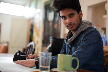 Portrait confident young male college student studying in cafe