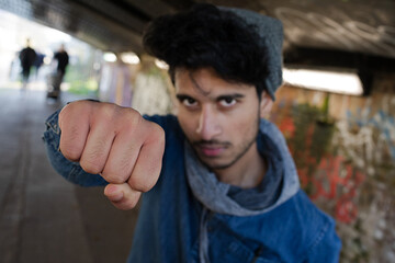 Portrait tough young man punching in urban tunnel