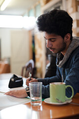 Portrait confident young male college student studying in cafe