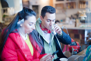 Young couple using smart phone at cafe window