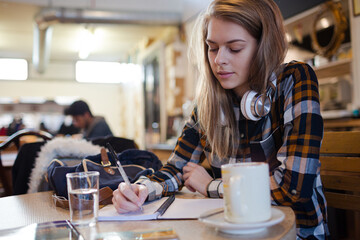 Portrait confident young female college student studying at cafe table