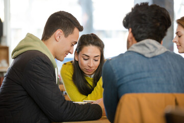 Young adult friends using smart phones at cafe table