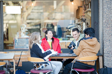 Young adult college students with digital camera at sidewalk cafe