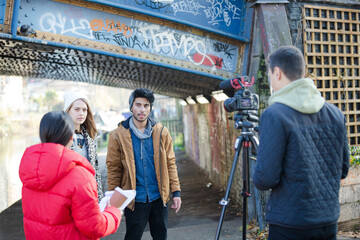 Young adults vlogging under urban bridge