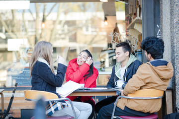 Young adult friends talking at sidewalk cafe