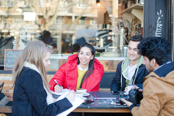 Young adult friends talking at sidewalk cafe