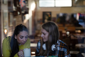 Young female college students studying at laptop in cafe window