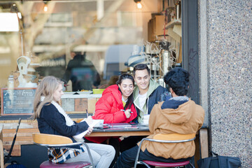Young adult college students with digital camera at sidewalk cafe
