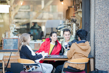 Young adult college students with digital camera at sidewalk cafe
