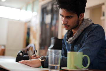 Portrait confident young male college student studying in cafe
