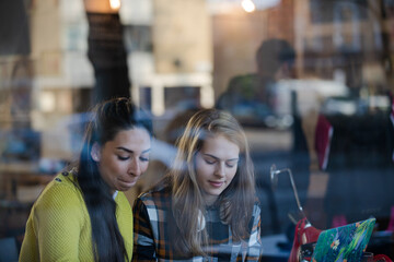 Young female college students studying at laptop in cafe window