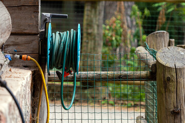 Garden water hose reel hung on the wooden wall of a log farm building, closeup