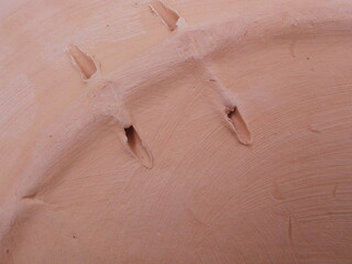 Holes on the back of a decorative ceramic plate: a thread can be passed through them to hang the plate on a wall