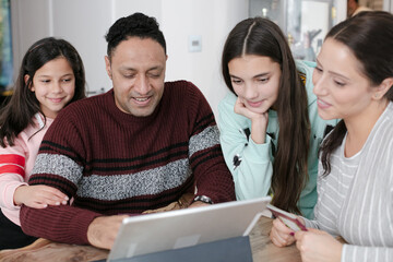 Family using digital tablet at kitchen table