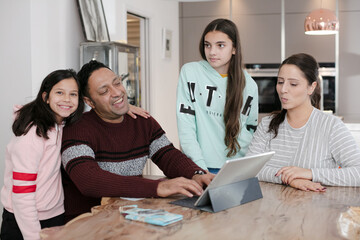 Family using digital tablet at kitchen table