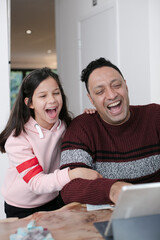 Father and daughter using digital tablet in kitchen