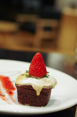 Strawberry on chocolate cupcake with sugar powder on white plate