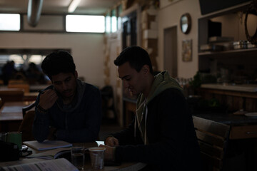 Portrait confident young male college students studying at cafe table