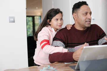 Father and daughter using digital tablet in kitchen