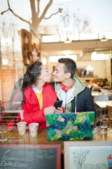 Young couple using smart phone and laptop in cafe