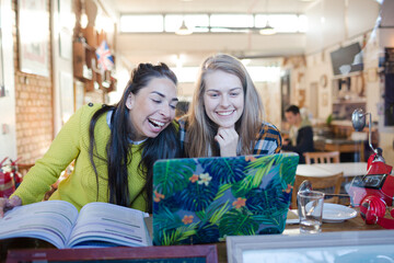 Young female college students studying at laptop in cafe window