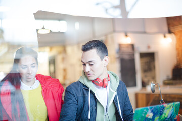 Young couple using smart phone at cafe window