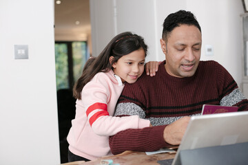 Father and daughter using digital tablet in kitchen