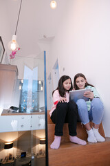Sisters using digital tablet on stairs at home
