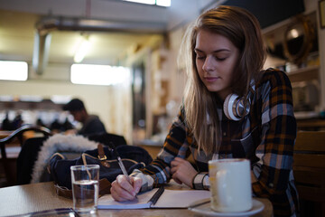 Portrait confident young female college student studying at cafe table