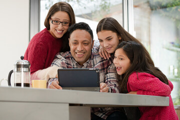 Happy family using digital tablet at kitchen table