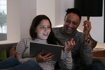 Couple relaxing, using digital tablet on living room sofa