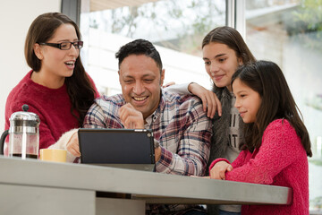 Happy family using digital tablet at kitchen table