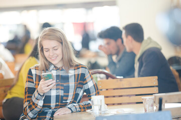 Smiling young woman using smart phone in cafe