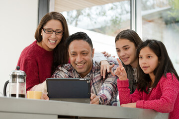 Happy family using digital tablet at kitchen table