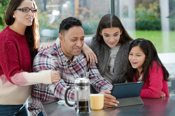 Happy family using digital tablet at kitchen table