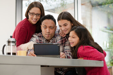 Happy family using digital tablet at kitchen table