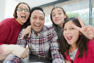 Playful family taking selfie with  in morning kitchen