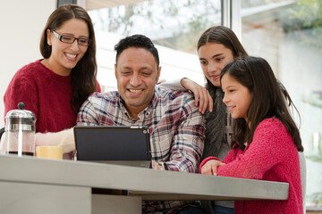 Happy family using digital tablet at kitchen table