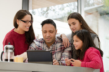 Happy family using digital tablet at kitchen table