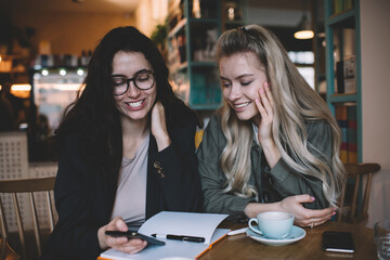 Young women browsing smartphone in cafeteria