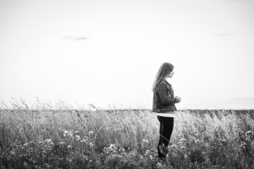 black and white of young woman praying in field with copy space