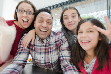 Playful family taking selfie with  in morning kitchen